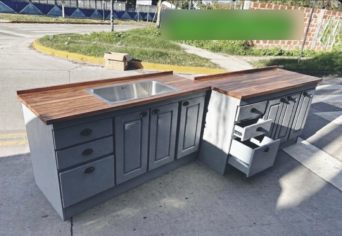 Bajomesada de cocina gris con pileta de acero, puertas con tablero, cajones abiertos y mesada de madera, con la marca Muebles de Pino sobre la foto