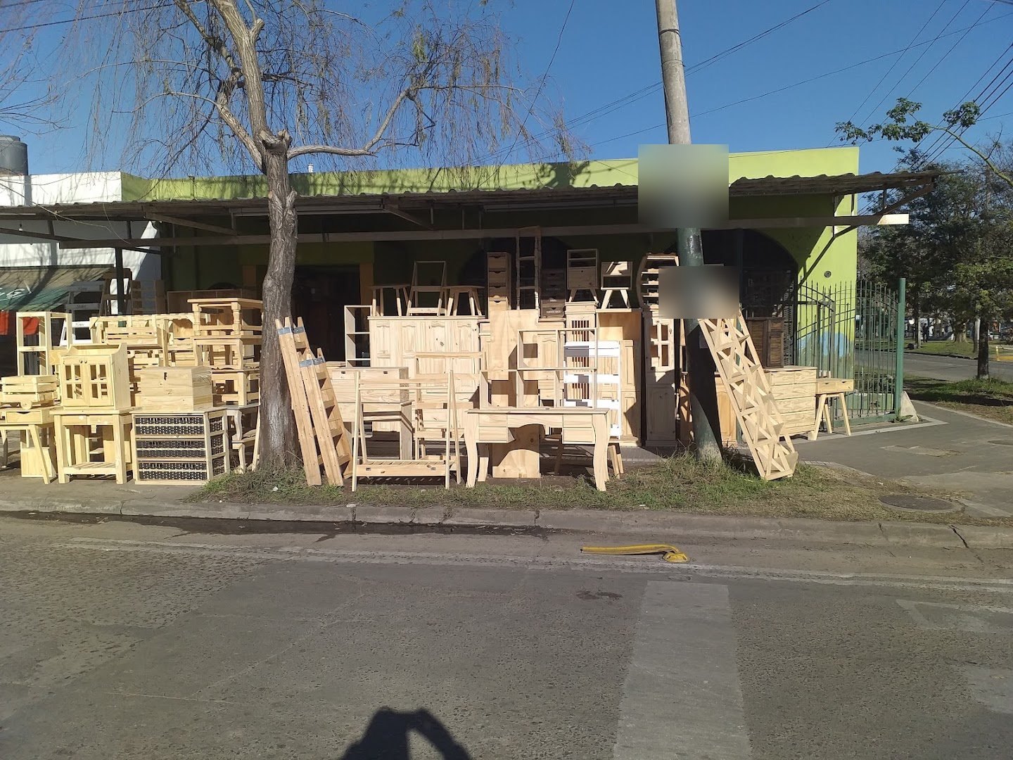 La esquina del local en tu zona, con la fachada verde y los muebles de pino sobre la vereda