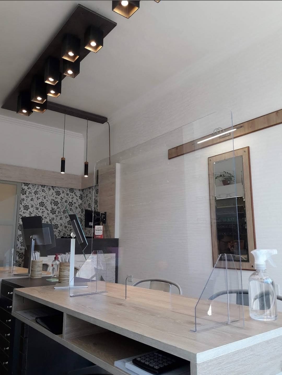 Interior de la óptica en tu zona: luces de techo, mostrador de madera y un espejo en la pared