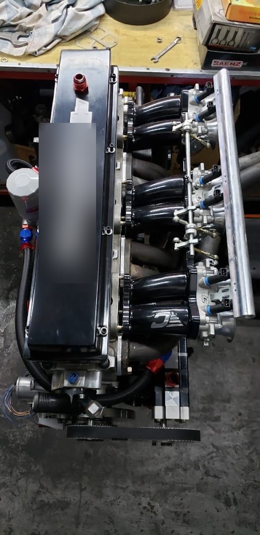 Motor de seis cilindros en línea visto desde arriba: tapa de válvulas negra con el logo de Chevrolet, seis tubos de admisión negros, tres cuerpos de aceleración dobles y riel de inyectores plateado