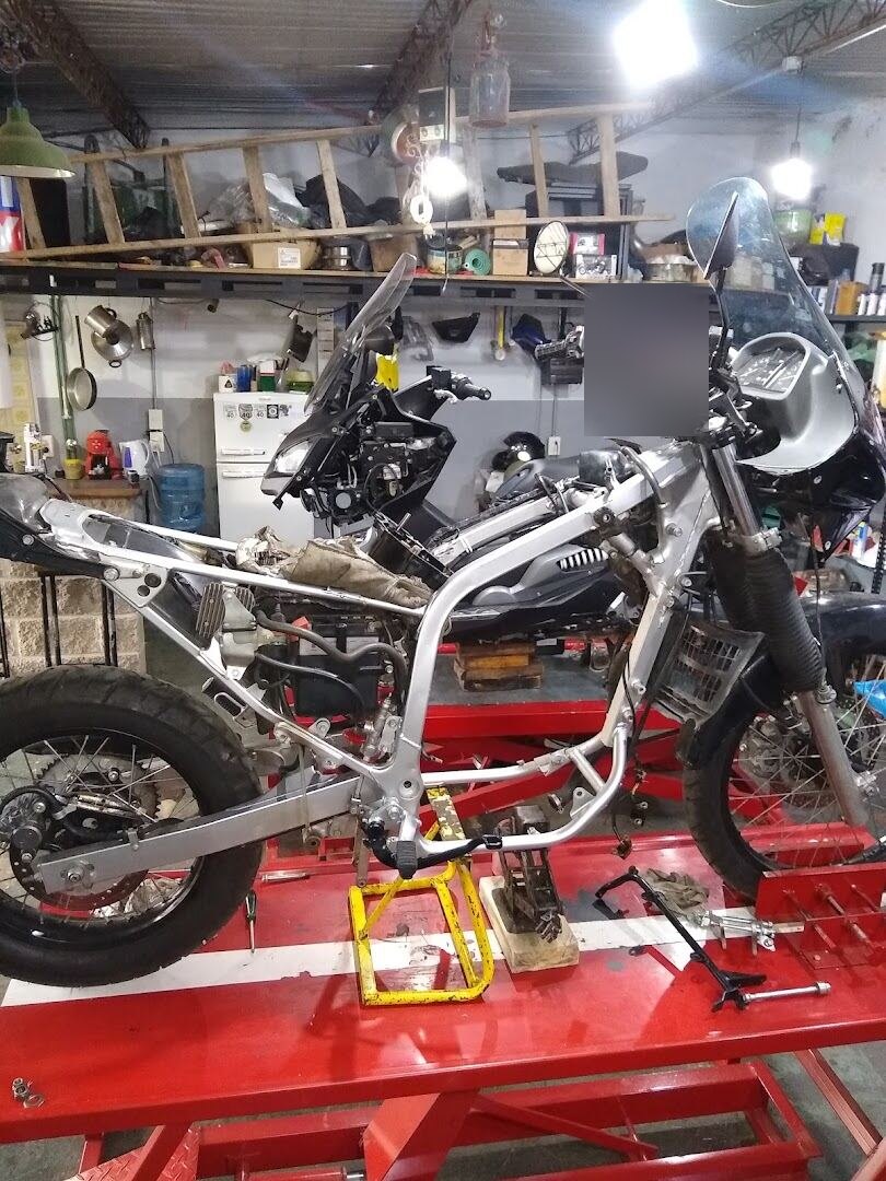 Chasis de moto desnudo montado en el taller, con la suspensión delantera a la vista para su reparación