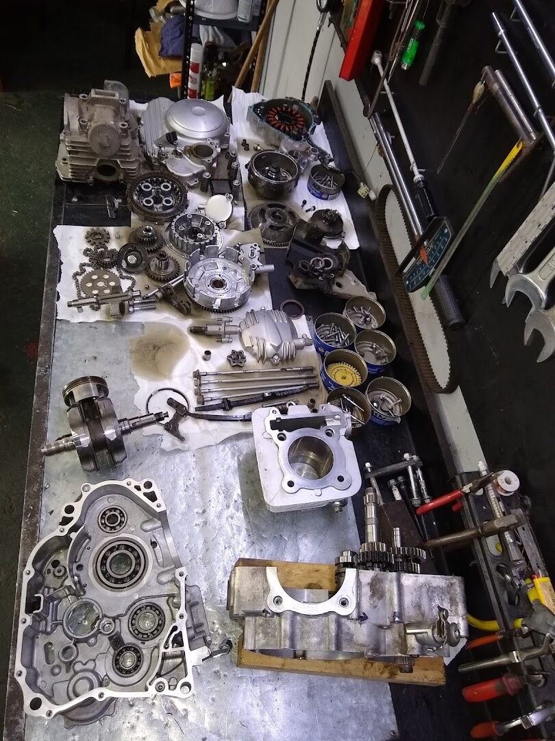 Motor de moto completamente despiezado sobre la mesa de trabajo del taller, con cada pieza ordenada para su revisión